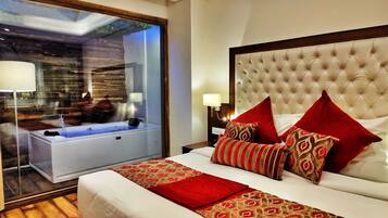 Quarto de hotel com uma cama grande, banheiro separado com banheira e vista para uma construção de madeira lá fora.