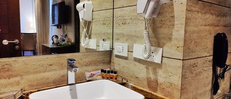 A bathroom with a large mirror, a sink, a hairdryer, and a telephone.