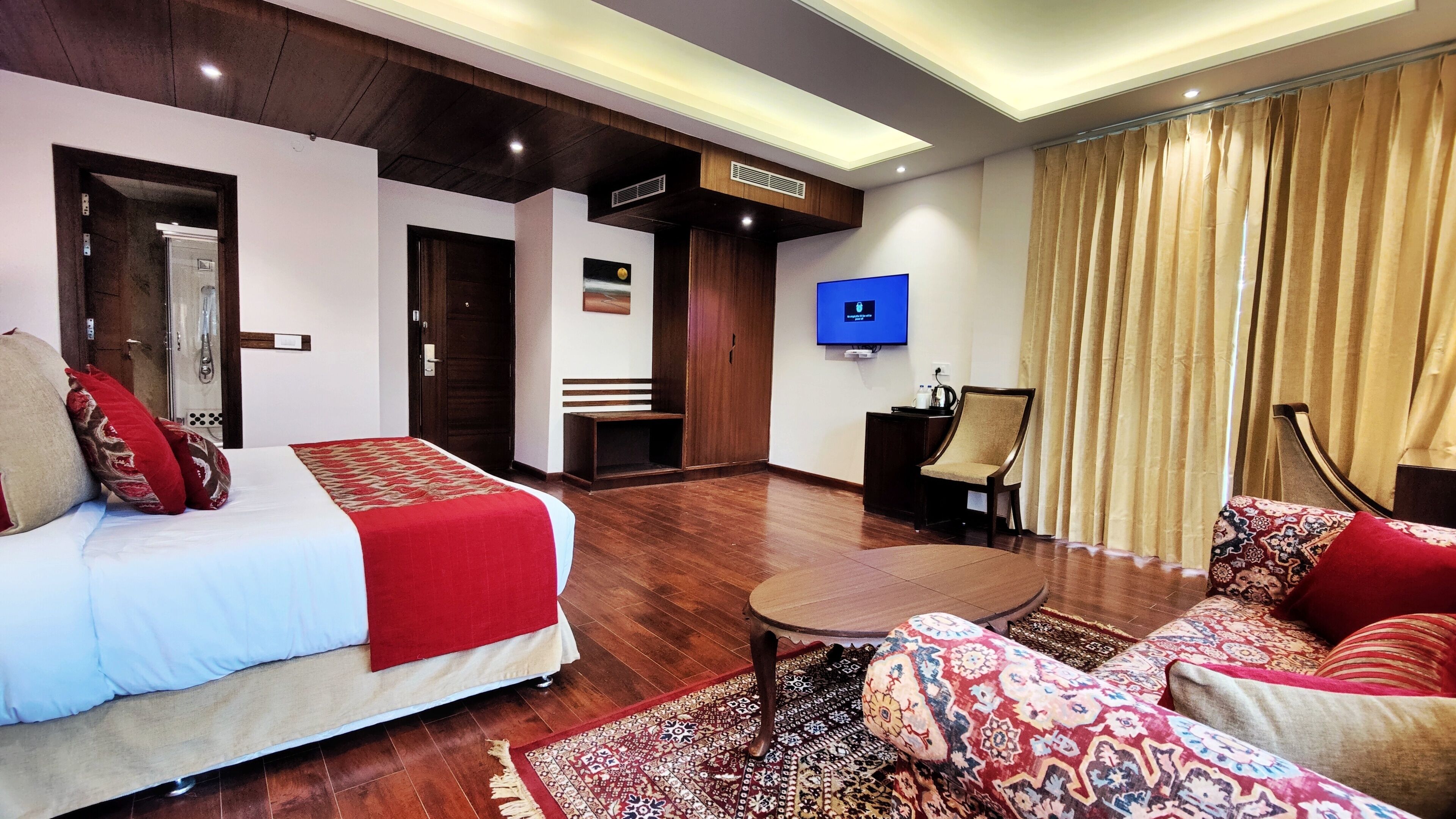 Een hotelkamer met een bed, een bank, een televisie en een bureau.