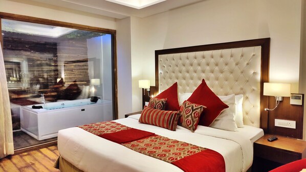 A hotel room with a large bed, a separate bathroom with a bathtub, and a view of the outside. - Royale Retreat Hotel & Spa Near Mall Road (Shimla)