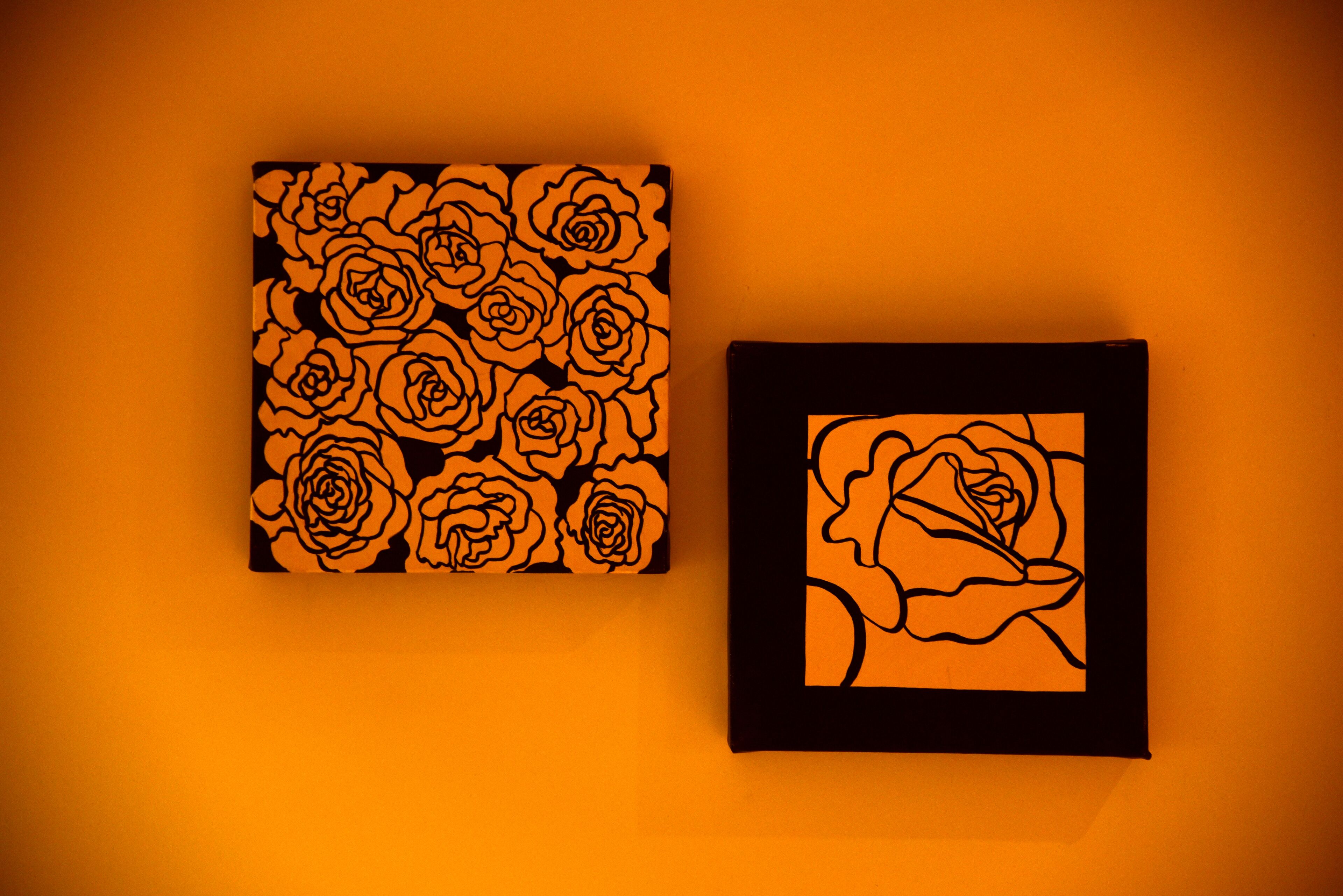 Twee ingelijste kunstwerken met rozenprint, waarvan één met meerdere rozen en de andere met een enkele roos.