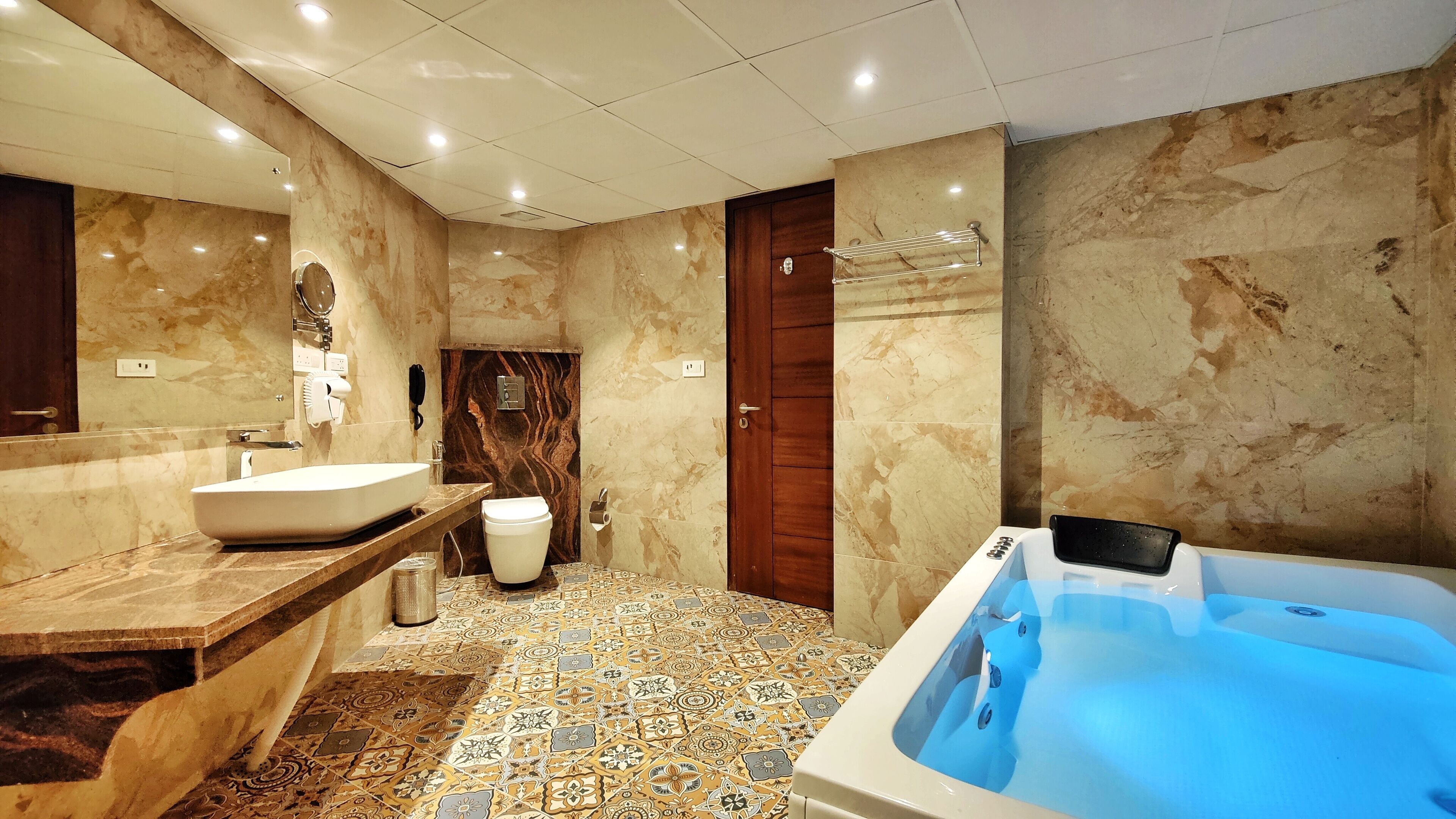 A modern bathroom with a large sink, toilet, and a jacuzzi tub.