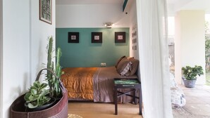 A compact bedroom with a bed, a small table, and a potted plant. - Garden Studio 55 s.m. (Chalandri)