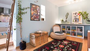 A modern living room with a wooden chest, a cushioned chair, and a bookshelf. - Garden Studio 55 s.m. (Chalandri)