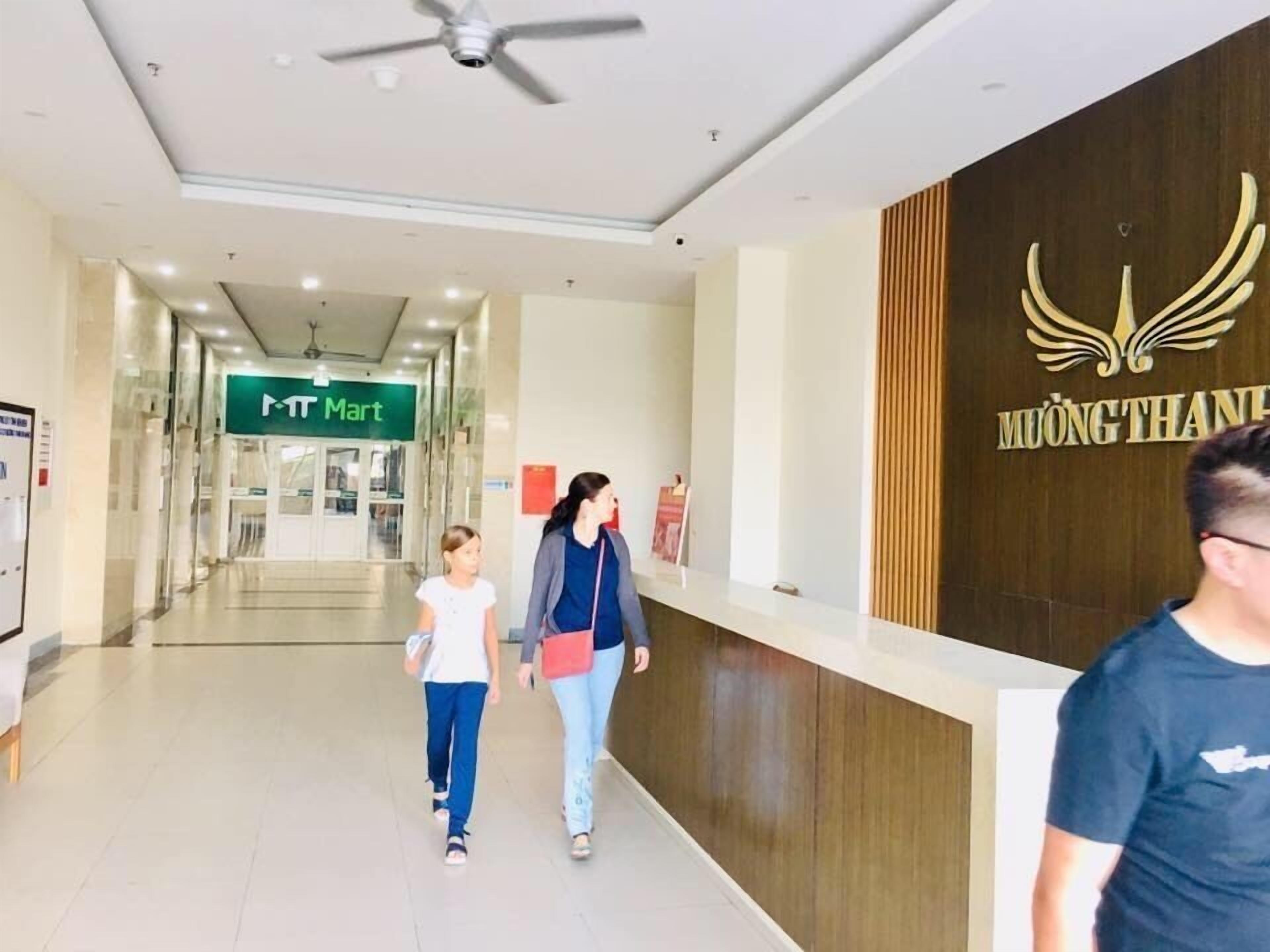 A hallway with a ceiling fan, a reception desk with a logo, and a sign for a nearby 'MT Mart'.
