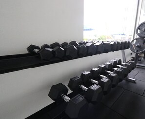 Una hilera de mancuernas negras sobre un soporte en un gimnasio.