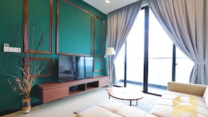 Una sala de estar moderna con una pared de acento color turquesa, un televisor de pantalla plana, un sofá y una pequeña mesa redonda.