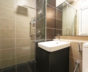 Un baño moderno con cabina de ducha de vidrio, un lavabo blanco y un espejo grande.