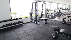 Un gimnasio con equipo de ejercicio, ventanas amplias y vistas al exterior.