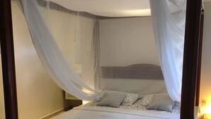 Un lit à baldaquin avec des rideaux, du linge de lit blanc et un cadre en bois.