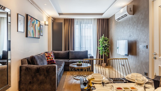 Ein modernes Wohnzimmer mit einer Couch, einem Esstisch für vier Personen und einem an der Wand befestigten Fernseher.