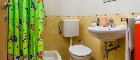A bathroom with a toilet, bidet, sink, and a mirror.
