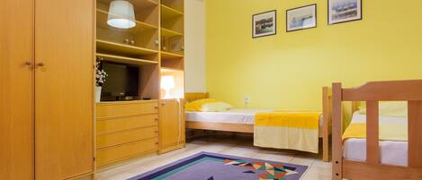 A bedroom with a bed, a wooden wardrobe, a desk, and a chair.