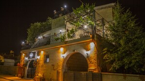 A historic building with a stone facade, arched entrance, and a balcony with potted plants. - Capiedra Hotel (Nevsehir)