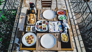 A table set for a meal with various dishes, including bread, olives, and a plate of food. - Capiedra Hotel (Nevsehir)