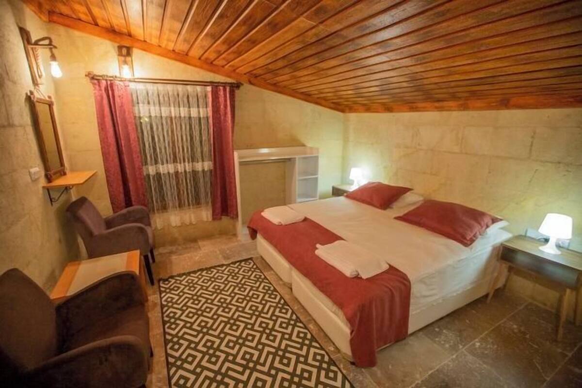 Ein Schlafzimmer mit einem Bett, einem Sessel, einem Schreibtisch, einem Spiegel und einem Teppich mit Muster.
