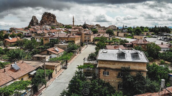 A town with traditional architecture, narrow streets, and a prominent rocky hill in the background. - Capiedra Hotel (Nevsehir)