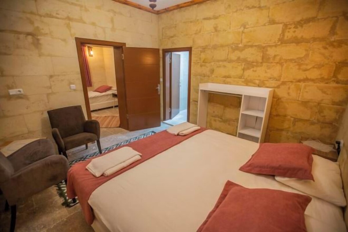 Una camera da letto con un letto, una sedia, un armadio e una porta che dà su un'altra stanza.