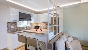 Une cuisine moderne avec des armoires blanches, un plan de travail en bois et une cuisinière intégrée. On y trouve également un coin repas avec une table et deux chaises.