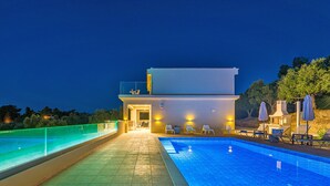 Un espace piscine comprenant une piscine, des chaises longues et un bâtiment doté d’un balcon.