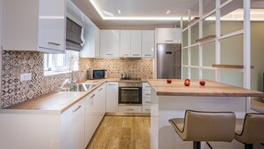 Une cuisine moderne avec des meubles blancs, un plan de travail en bois et un four encastré.