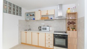Une cuisine compacte équipée d’un four à micro-ondes, d’une cuisinière, d’un évier et d’armoires en bois.