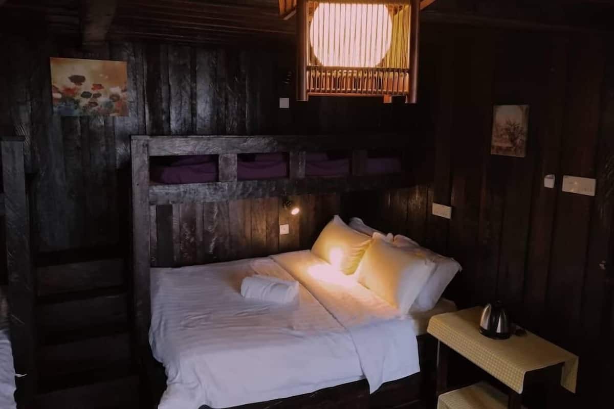 A cozy wooden cabin room with a bed, a small table, and a hanging light fixture.