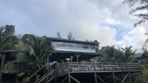 A wooden structure with a balcony, surrounded by palm trees and a cloudy sky. - Tim's Seaside Hideout Resort (Miri)