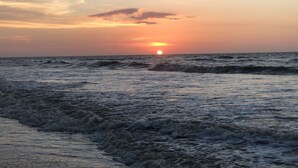 A sunset over the ocean with waves approaching the shore. - Tim's Seaside Hideout Resort (Miri)