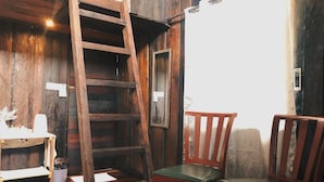 A wooden interior with a wooden ladder, two wooden chairs, and a small table with a white object on it. - Tim's Seaside Hideout Resort (Miri)