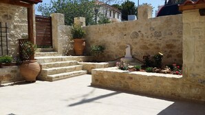 A stone staircase leading to a door, surrounded by potted plants and a water feature. - Cozy traditional stone-house at Cretan nature .Stunning... (Βασιλικη)