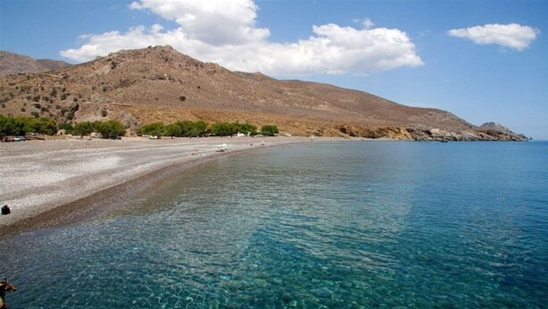 A beach with clear blue water, a sandy shore, and a rocky hillside in the background. - Cozy traditional stone-house at Cretan nature .Stunning... (Βασιλικη)