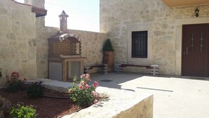 A courtyard with stone walls, a bench, a potted plant, and a door. - Cozy traditional stone-house at Cretan nature .Stunning... (Βασιλικη)