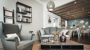 A modern living room with a grey armchair, a sofa, a coffee table, and a bookshelf. - Hotel Freihof am Roland (Wedel)