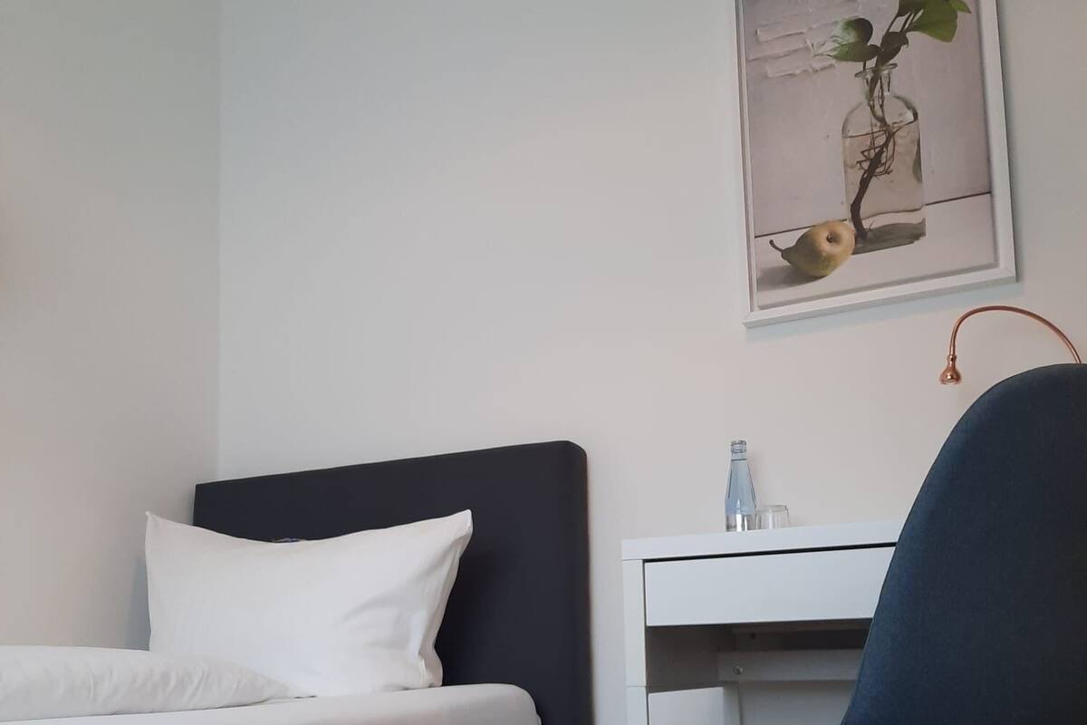 A bedroom with a bed, a desk, and a chair.
