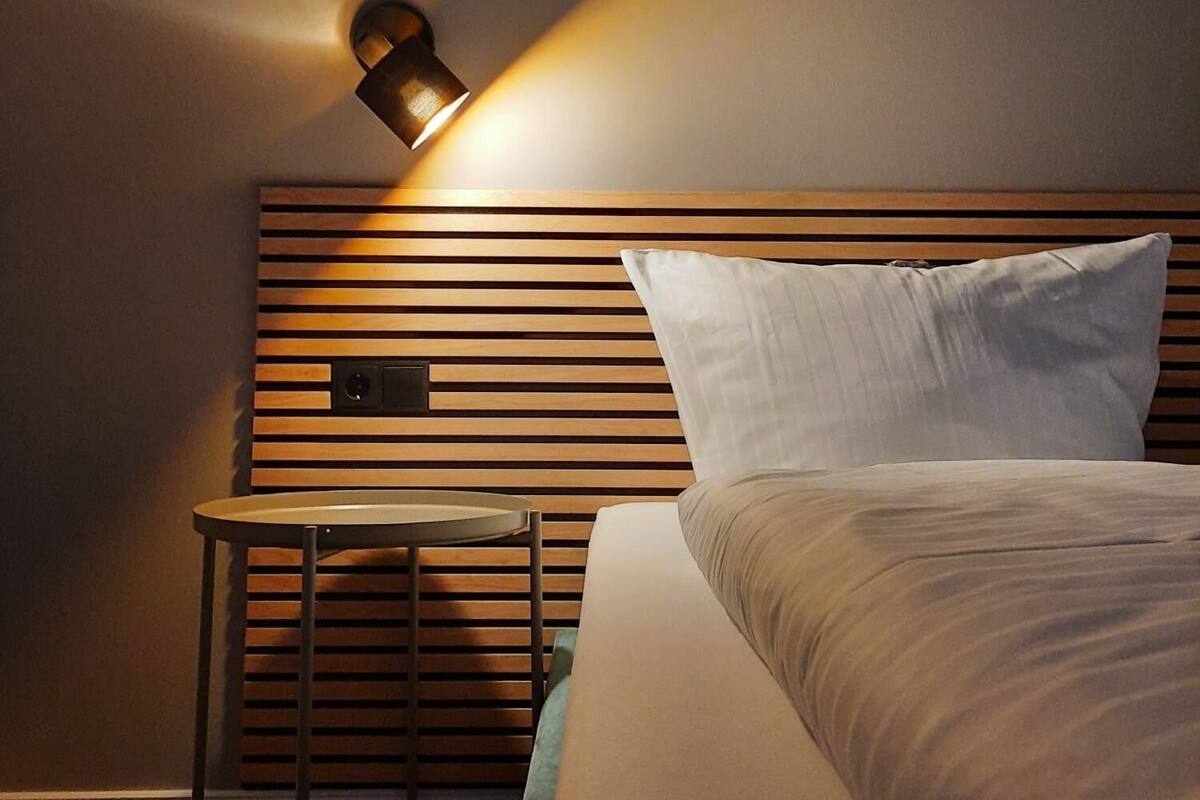 A bedroom with a wooden headboard, a bedside table, and a lamp.