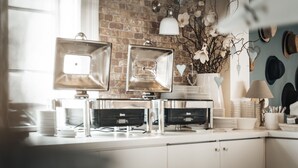 A modern kitchen with a brick wall, stainless steel appliances, and a decorative wall hanging. - Hotel Freihof am Roland (Wedel)