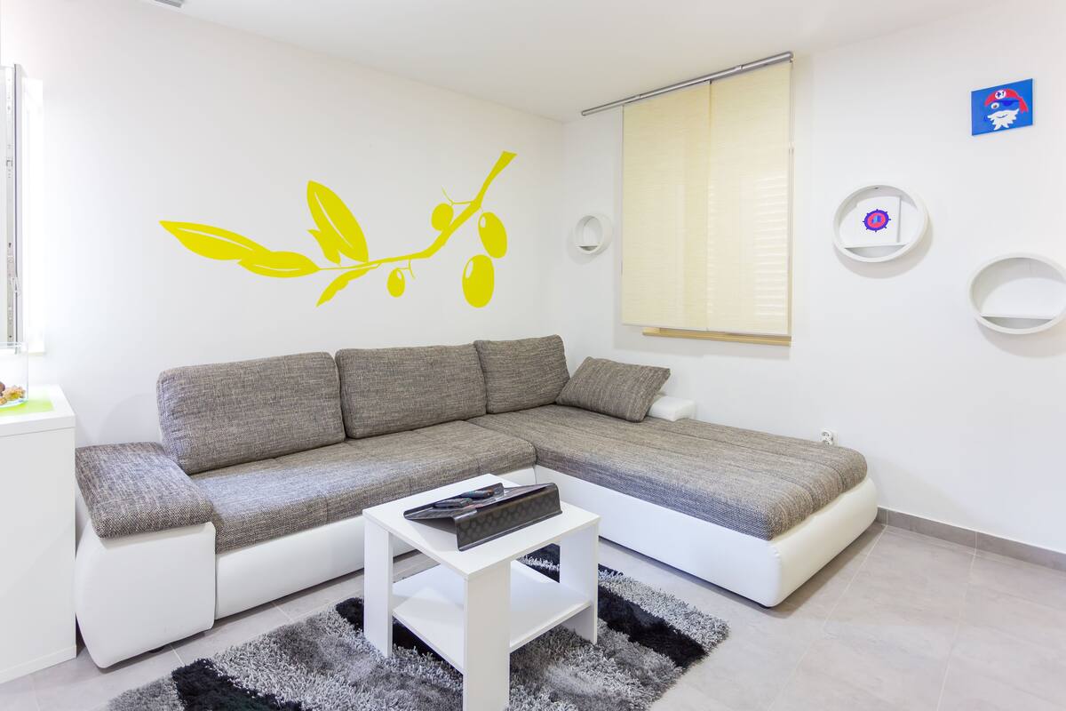 A modern living room with a grey sectional sofa, a white coffee table, and a black and white rug.