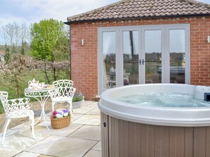 A hot tub, outdoor seating, and a brick building with glass doors.
