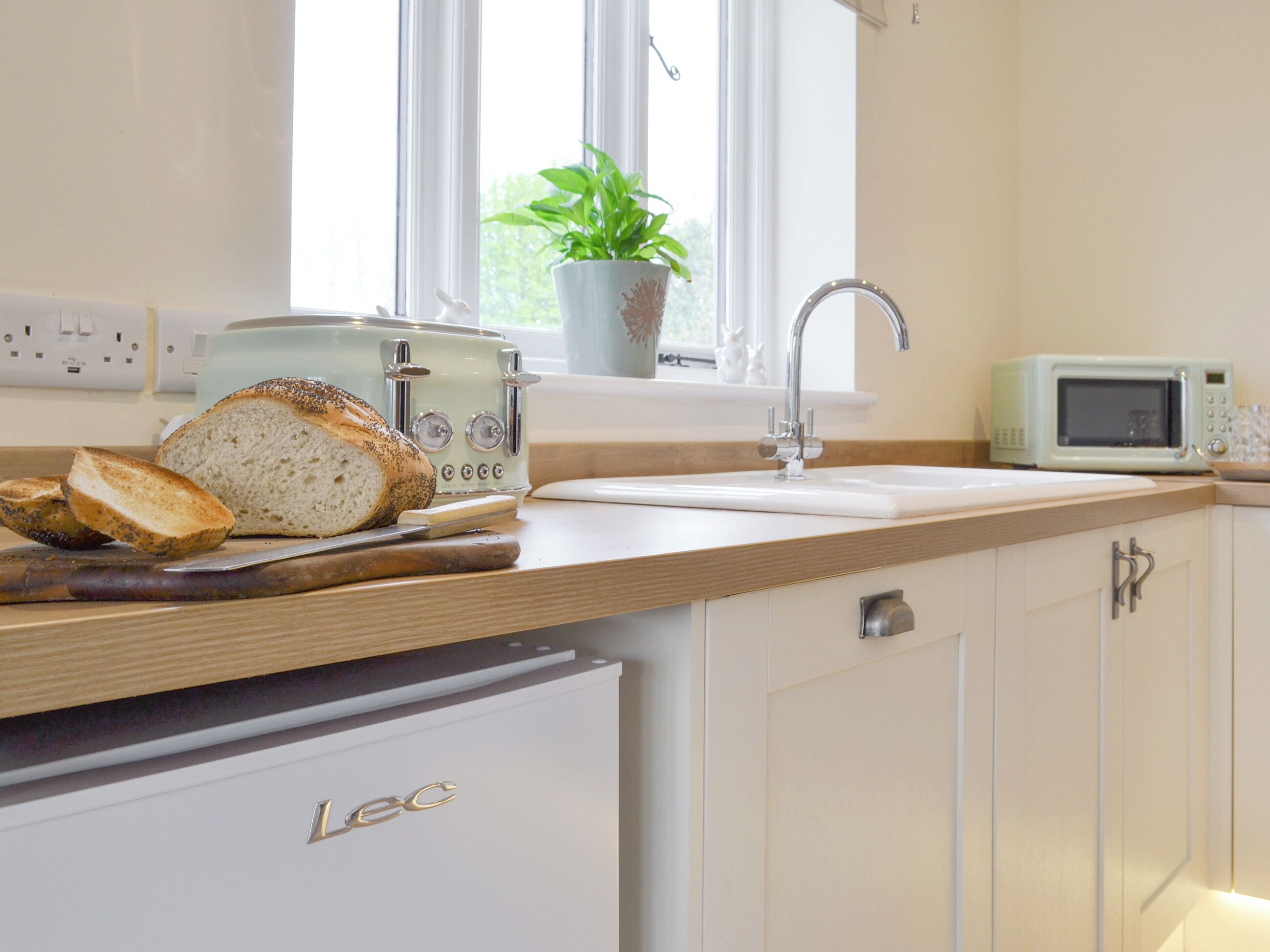 Eine Küche mit Toaster, Mikrowelle, Spüle und einem Schrank mit der Aufschrift 'Lec'.