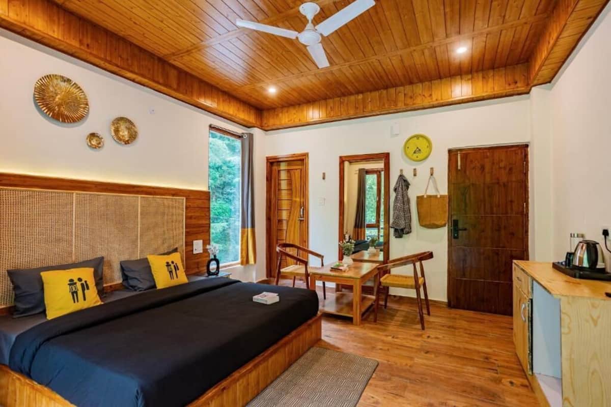 A cozy bedroom with a large bed, wooden ceiling, and a desk area with a chair and table.