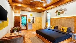 A bedroom with a wooden ceiling, a bed with a dark blue bedspread, and a wooden headboard. - The Hosteller Kasol (Bhuntar)