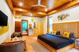 A bedroom with a wooden ceiling, a bed with a dark blue bedspread, and a wooden headboard.