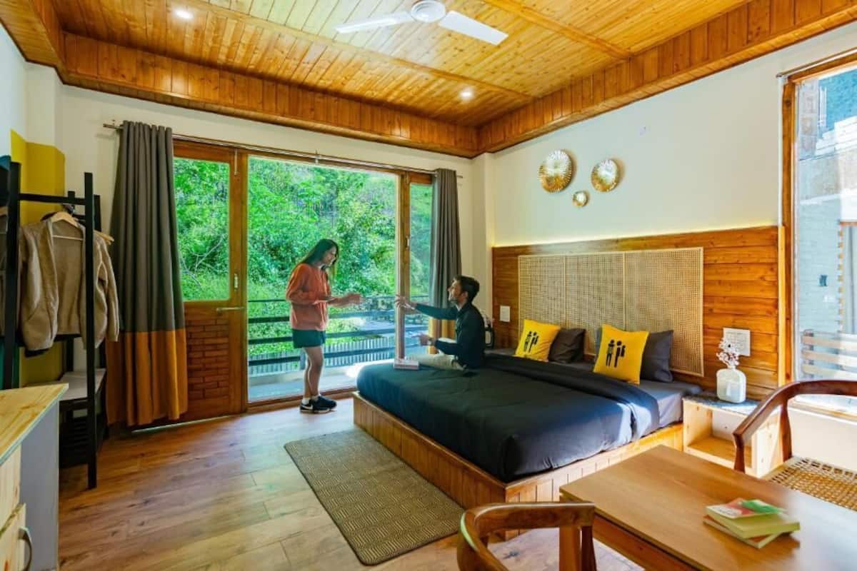 A wooden-floored bedroom with a bed, a desk, and a chair.