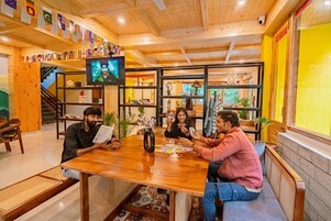Interior de madera con un grupo de personas jugando cartas en una mesa.
