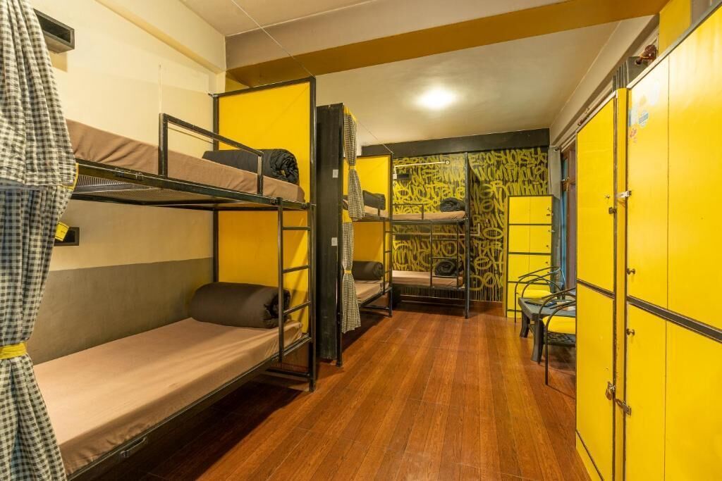 A dormitory room with bunk beds, a small table, and yellow lockers.