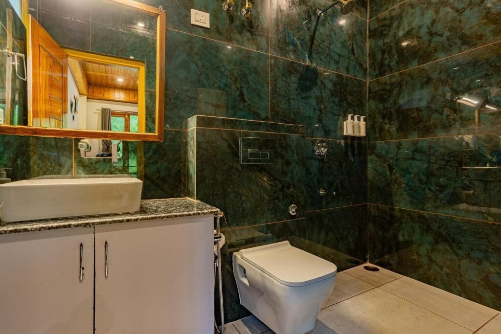 A bathroom with a marble wall, a sink, a toilet, and a shower area.