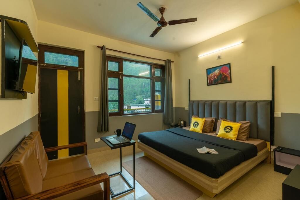 Un dormitorio con cama, escritorio, computadora portátil, televisor y ventilador de techo.