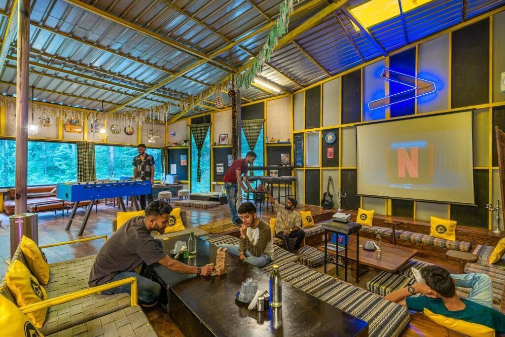 A spacious indoor area with a foosball table, comfortable seating, and a large screen displaying the letter 'N'.