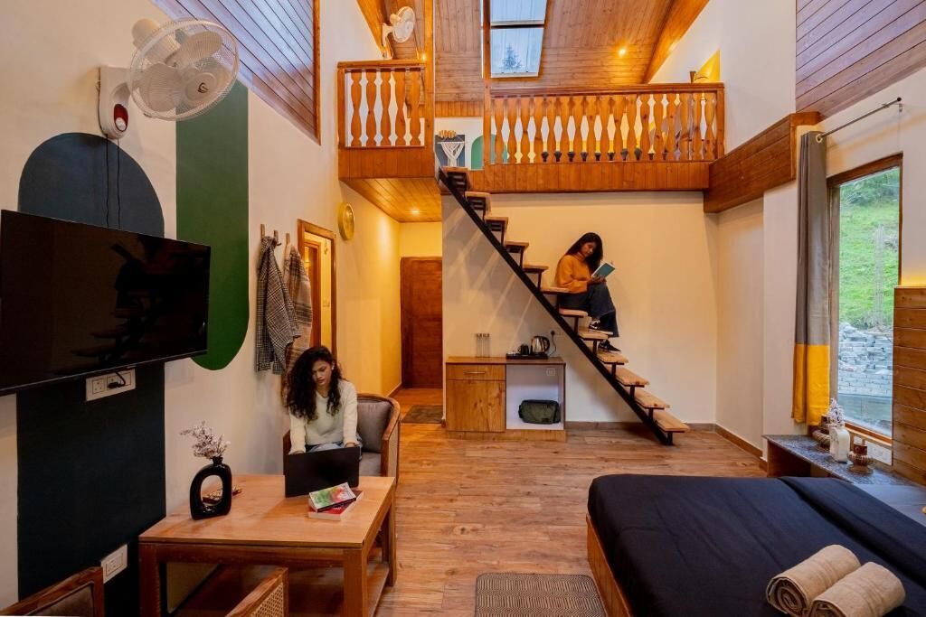 A cozy room with a bed, a TV, a staircase, and a balcony.